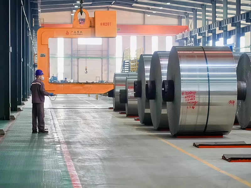 Worker handling 5754 Aluminum Coil with 20T lifting clamp in finished goods warehouse