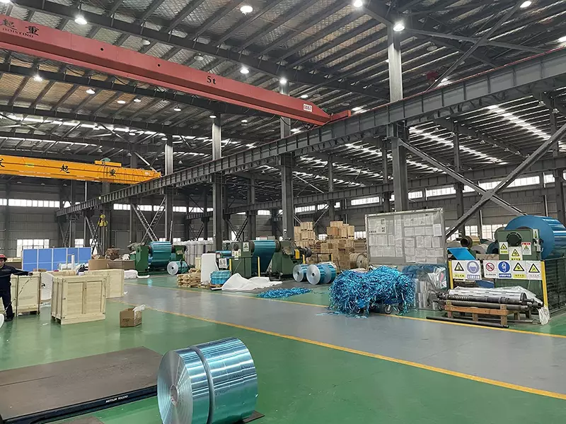 Oficina de produção de aletas de alumínio com bobinas de metal e pontes rolantes.