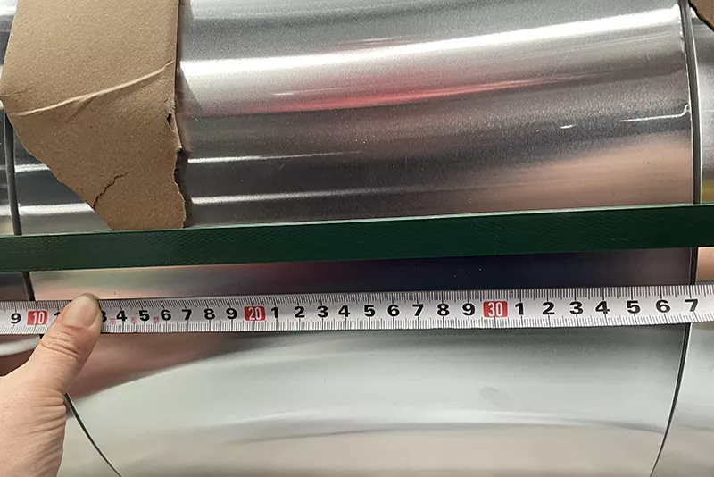 Inspector de calidad midiendo el ancho de la bobina de aluminio con una herramienta de medición de precisión.