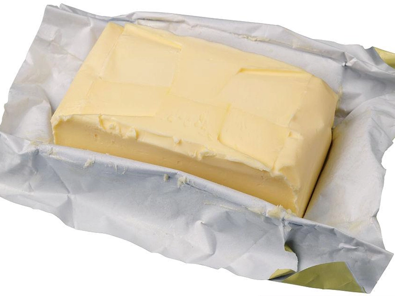 Butter wrapping aluminum foil shown in a partially opened package around the butter block